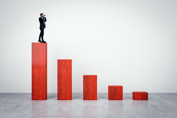 Businessman with binoculars standing on top of red chart made of wooden bricks on light background. Crisis, finance and business forecast concept.
