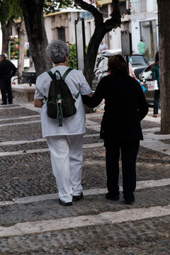 Osuna, Sevilla, cuidadora de anciana, paseando a mujer mayor, cogidas del brazo, vistas de espaldas
