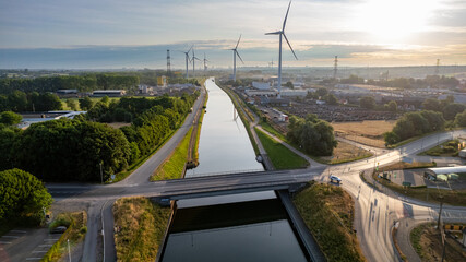 This aerial image captures a modern landscape at dawn, where renewable energy meets waterway...