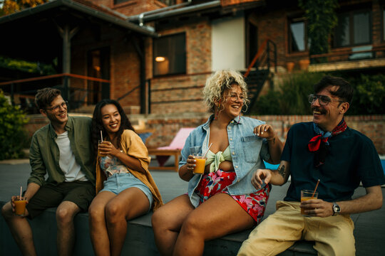 Friends with different backgrounds sharing stories, enjoying cool drinks, and making memories at a laid-back pool party