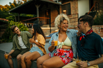 Friends with different backgrounds sharing stories, enjoying cool drinks, and making memories at a laid-back pool party