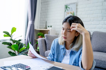 Young Asian woman is stressed because she is looking at many bills and has no money to pay them....