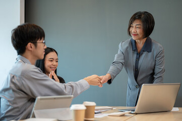 Obraz premium A professional female boss is shaking her hand with a young businessman during the meeting.