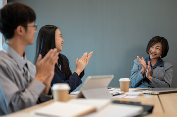 Group of satisfied businesspeople are applauding and celebrating during the meeting together.