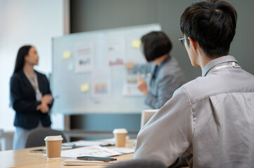 A concentrated young Asian businessman is listening carefully to a presentation in a meeting.