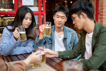 Group of happy Asian friends are enjoying beers at a restaurant or bar in the city together.