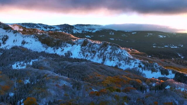 First light Kebler Pass Crested Butte Gunnison Colorado seasons crash aerial drone early fall aspen tree red yellow orange forest winter first snow cold sunrise cloud Rocky Mountain peaks left motion