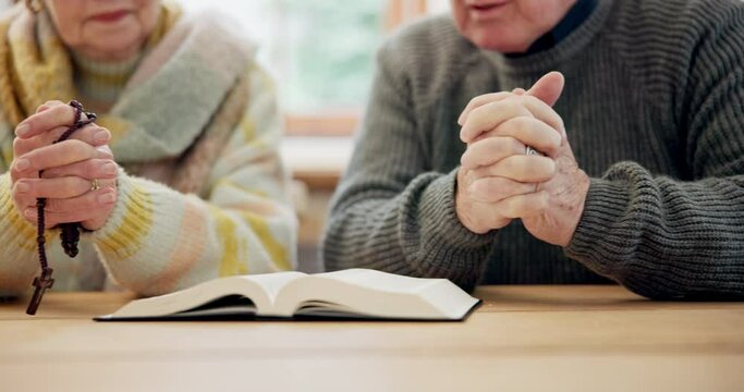 Hands, senior couple and bible for praying, faith and worship Jesus Christ, holy spirit and God at home. Closeup, rosary and reading gospel books for christian prayer, gratitude or spiritual religion