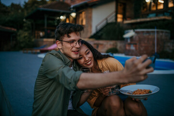 Loving caucasian man and Asian woman enjoying wine and pasta together in the backyard
