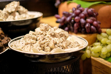 Succulent meat kebabs and creamy salads on display, the richness inviting. The indulgence of meat feasts contrasts with vegan trends.