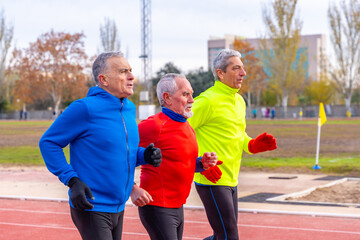 Senior sportive men running together in an athletics field
