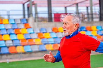 Senior man sprinting in an athletic field outdoors