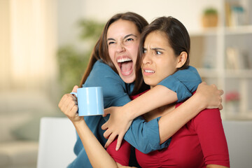 Excited woman hugging to an upset friend - obrazy, fototapety, plakaty