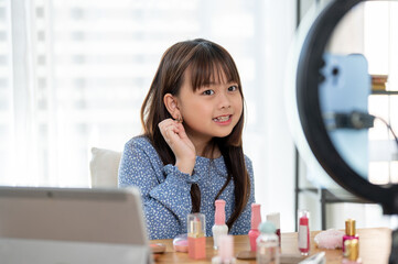 An adorable young Asian girl kid influencer is recording her kid makeup tutorial and get ready video