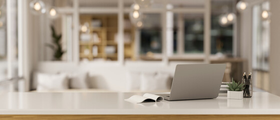 Workspace with a laptop computer and accessories on a white tabletop in a modern, luxury living room