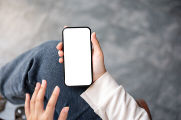Close-up image of a woman relaxing outdoors and using her smartphone. A phone white-screen mockup