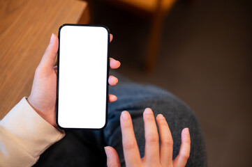 Close-up image of a woman using her smartphone indoors. A white-screen smartphone mockup