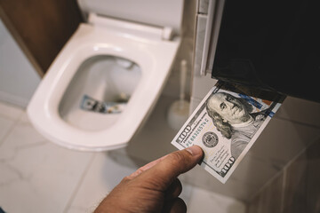 Flush money down the toilet, throws dollar bills in the toilet, loss concept, close up, selective...