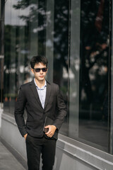 Asian Businessman walking outside office building.