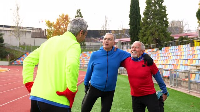 Mature men talking and stretching in a running outdoor track
