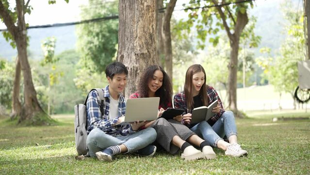 Several generations of bright young students are preparing for exams in the park. read books together and use laptop Education concept, smart student is having happy outdoor lesson with teacher.