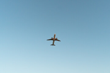 Close-up of a white plane taking off against a blue sky, bottom view. Travel by air