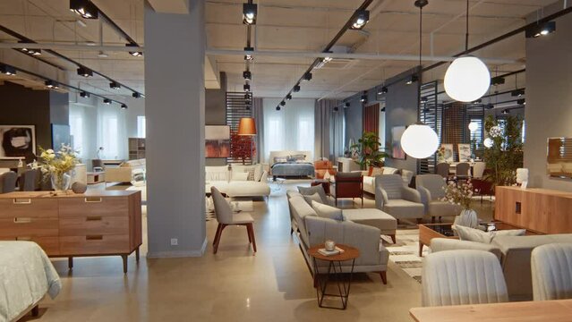 Dolly shot of vast furniture showroom filled with different pieces of furniture of various sizes and colours