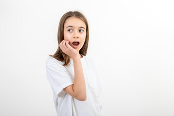 A girl with mouth wide open holds her hand near face on a white background.