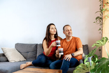 happy couple on the sofa at home with a cup of drink