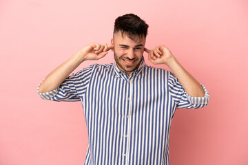 Young caucasian man isolated on pink background frustrated and covering ears