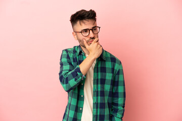 Young caucasian man isolated on pink background having doubts and with confuse face expression