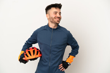 Young cyclist man isolated on white background posing with arms at hip and smiling - obrazy, fototapety, plakaty