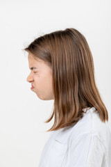 A teenager girl grimaces with displeasure on a white background, isolated.