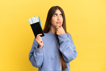 Naklejka premium Young caucasian woman holding a passport isolated on yellow background and looking up