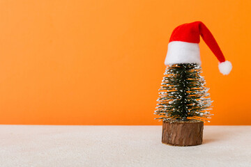 One small Christmas tree with santa hat on colored background. new year decoration with copy space