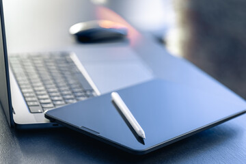 Digital tablet, stylus pen and laptop on the desktop, close up.