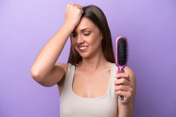 Young caucasian woman holding hairbrush isolated on purple background has realized something and intending the solution