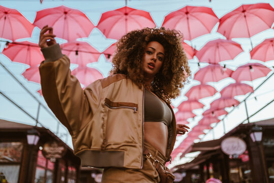 Beautiful woman dancing under pink umbrellas