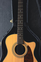Fototapeta premium Acoustic guitar in a protective case on a dark background, top view.