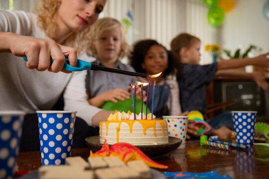 Woman lighting candles on birthday cake at home