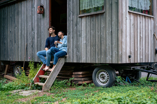 Smiling couple sitting in doorway of log cabin