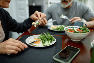 Couple eating fried eggs and salad for breakfast at home