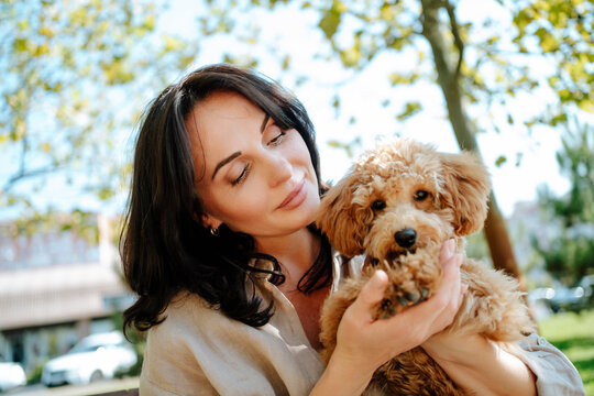 Loving woman holding poodle dog in park