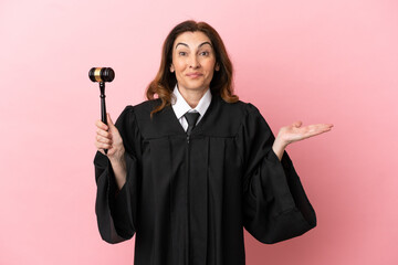 Middle aged judge woman isolated on pink background with shocked facial expression