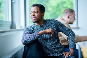 Thoughtful man looking out of window sitting in classroom