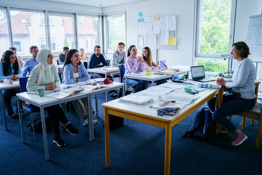 Smiling teacher teaching to multi-ethnic students in classroom
