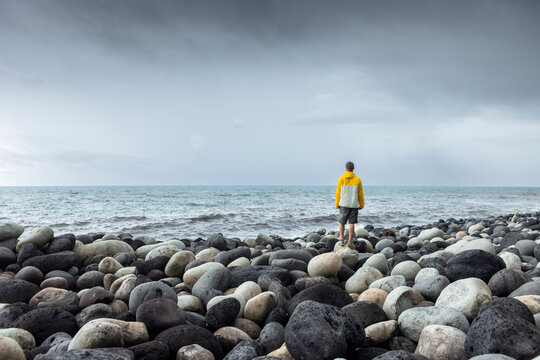 Man standing on rocks in front of sea under sky