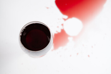 red wine in a transparent glass and spilled drink on a white background