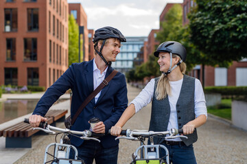 Spouses commuting through the city, talking and walking by bike on street. Middle-aged city...