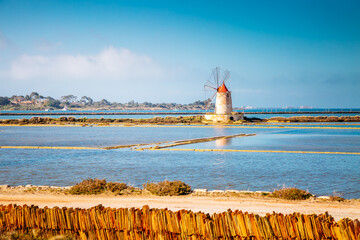 Ancient windmill for grinding salt in salt flats. Trapani province, Sicily, Italy, Europe. - obrazy, fototapety, plakaty